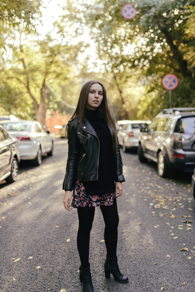 Street-style photo of a woman wearing a black leather biker jacket over a floral skirt